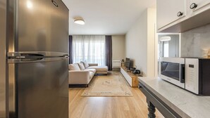 Una cocina moderna con electrodomésticos de acero inoxidable, una mesa de comedor de madera y un sofá en la sala.