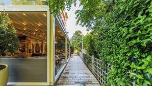 Un área de café al aire libre con mesas y sillas, un camino y una siega a un lado.