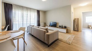 Una sala moderna con sofá, televisión y comedor.