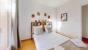 A neatly arranged bedroom with a bed, pillows, a bedside table, and wall decorations. - Edenhome + 1 parking lot (Colmar)