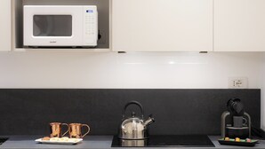 A kitchen with a white microwave, a kettle, and a coffee maker on the counter. - Amazing Tacito (Rome)