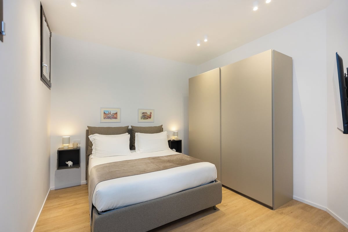 Ein modernes Schlafzimmer mit einem großen Bett, Nachttischen, einem Kleiderschrank und Wandbildern.