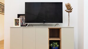 A modern entertainment unit with a flat-screen TV, framed artwork, and a potted plant. - Amazing Tacito (Rome)