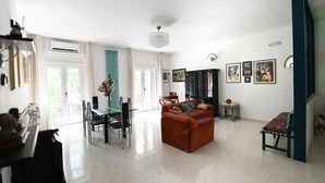 A spacious living room with a sofa, dining table, chairs, and a chandelier. - GuestHost - Roomy and bright 140 sqm apartment, accommodating up to 4 people, located on the first floor of a building without an elevator.The property is located in a semi-central area of ​​Matera, well-served by public transport and a short distanc (Matera)