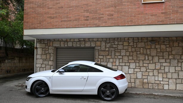 A white car parked in front of a building with a stone facade and a garage door. - GuestHost - Roomy and bright 140 sqm apartment, accommodating up to 4 people, located on the first floor of a building without an elevator.The property is located in a semi-central area of ​​Matera, well-served by public transport and a short distanc (Matera)
