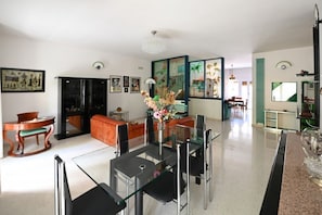 Amplia sala de estar con mesa de comedor de vidrio, asientos cómodos y obras de arte en las paredes.