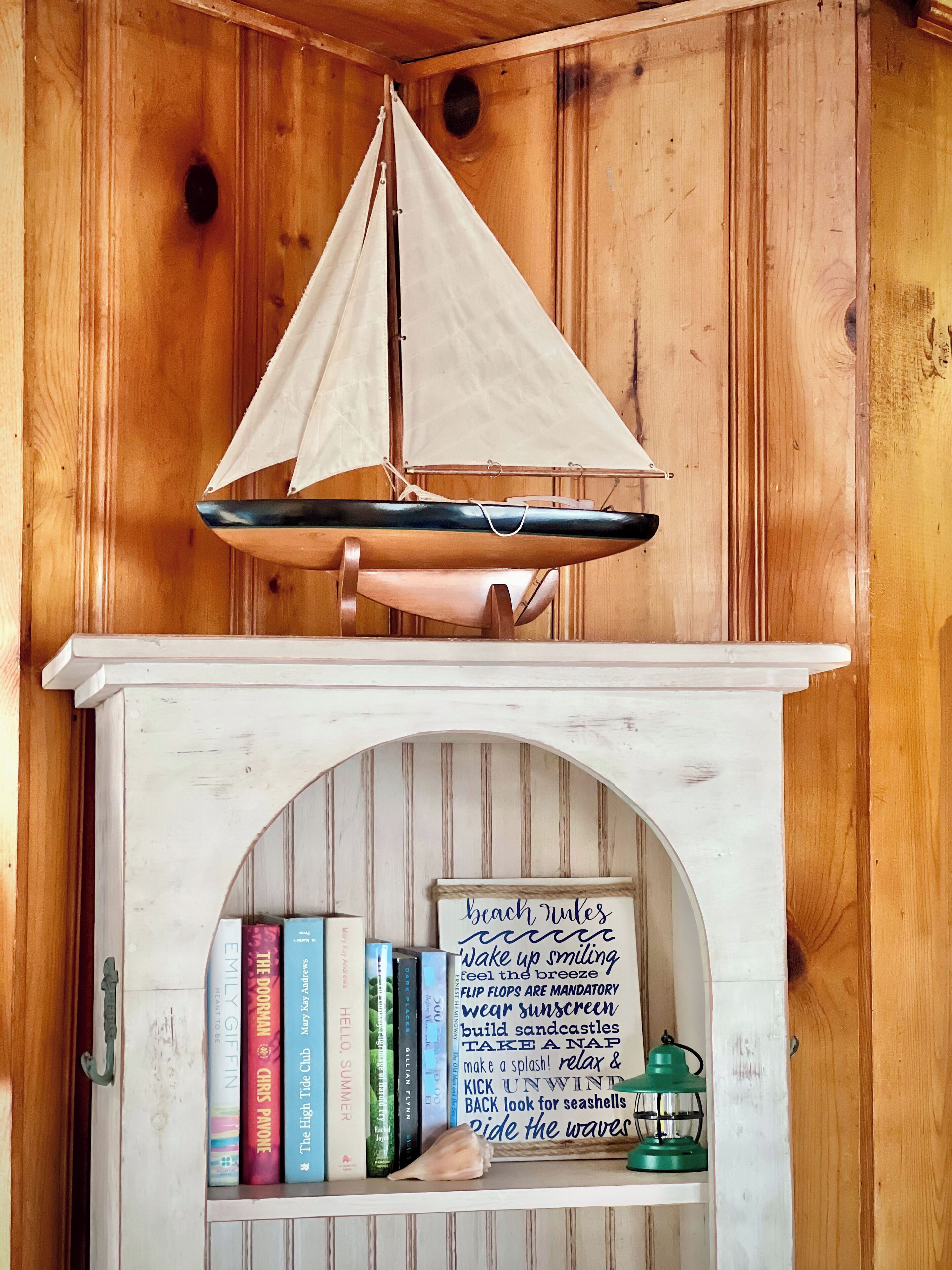 Uma estante com livros e uma placa com frases sobre a praia.