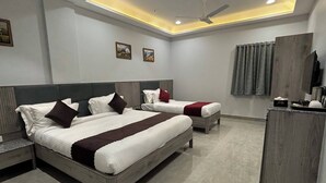 A modern hotel room with two beds, a ceiling fan, recessed lighting, and a small desk with a coffee maker. - The Byke Boutique - Amra Oasis Osian (Osian)