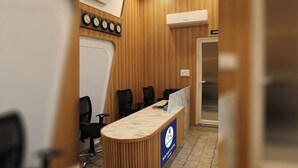 A conference room with a wooden panel wall, a marble reception desk, and a clock above it. - The Byke Boutique - Amra Oasis Osian (Osian)