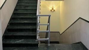 A staircase with a metal handrail, a light fixture on the wall, and a patterned floor. - The Byke Boutique - Amra Oasis Osian (Osian)