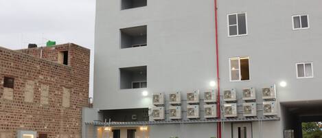 A multi-story building with a flat roof, a red vertical line, and multiple air conditioning units.