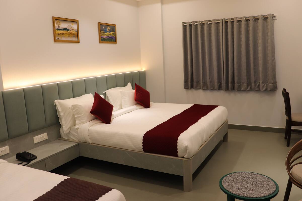 Una habitació d'hotel amb un llit, una taula de nit, una cadira i una taula rodona petita.