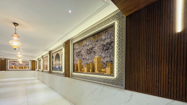 A hallway with marble flooring, framed artwork, wooden paneling, and hanging lights. - The Byke Boutique - Amra Oasis Osian (Osian)