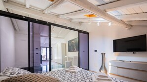 A modern bedroom with a bed, a TV, a vase, and a sliding door leading to a balcony. - [Caronda House Design] Free parking + Terrazzo (Catania)