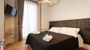 Ett modernt hotellrum med en säng, en platt-TV, ett skrivbord och ett stort fönster med gardiner.