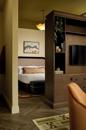 A hotel room with a bed, a TV, a wooden cabinet, and a plant. - The Hoxton, Dublin (Dublin)