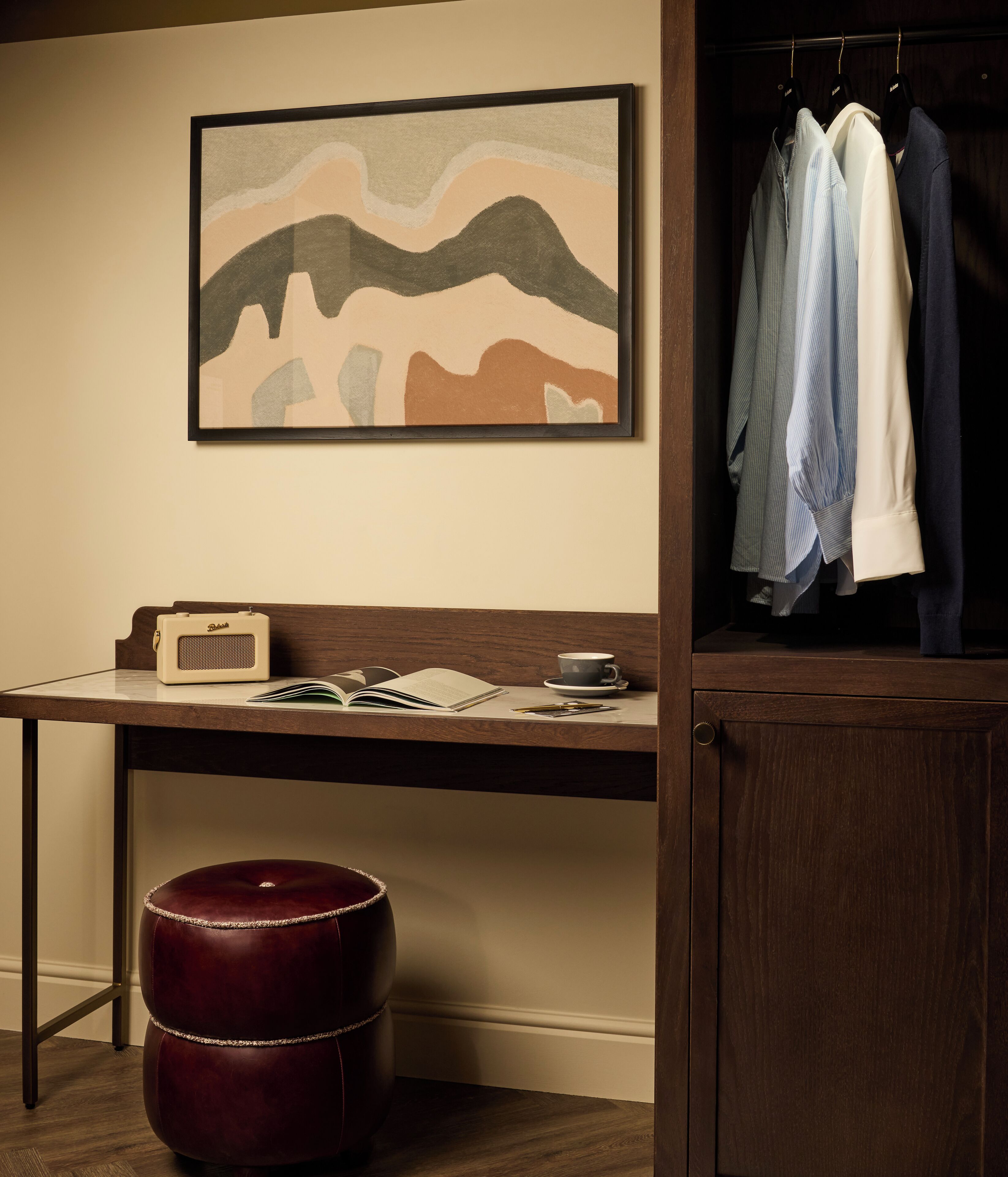A room with a desk, a chair, a bookshelf, a wardrobe, and a hanging coat rack.