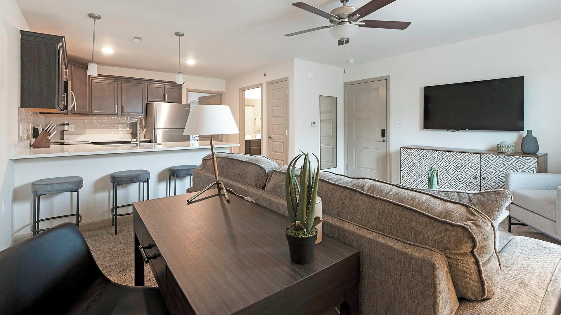 A modern living space with a kitchen, dining area, and seating.