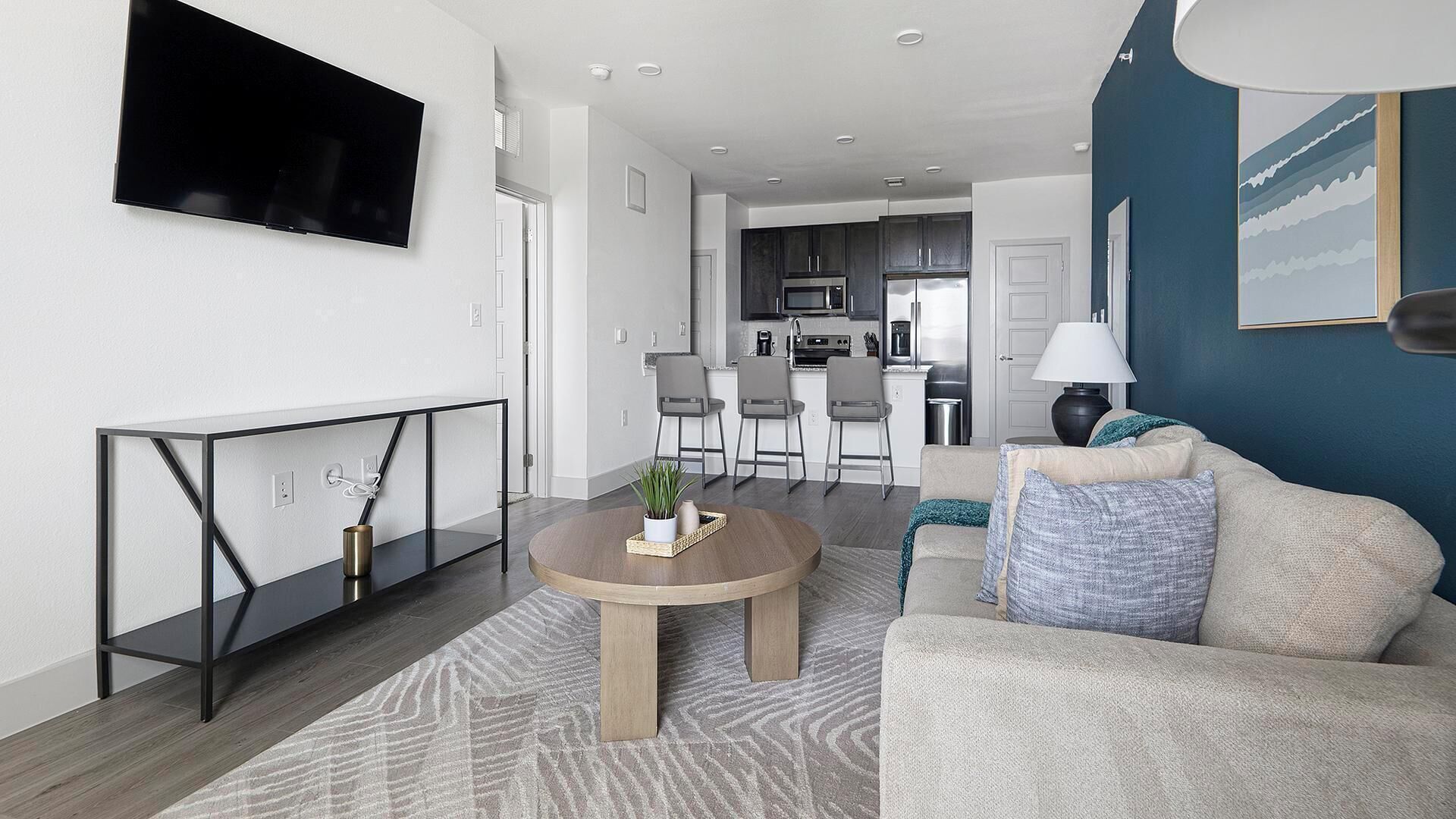 A modern living room with a sofa, a coffee table, and a TV mounted on the wall.