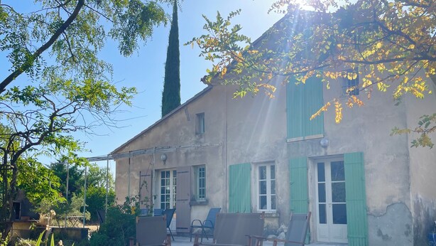A rustic building with a garden patio featuring wooden furniture. - The farmhouse at the foot of the Ventoux (Carpentras)