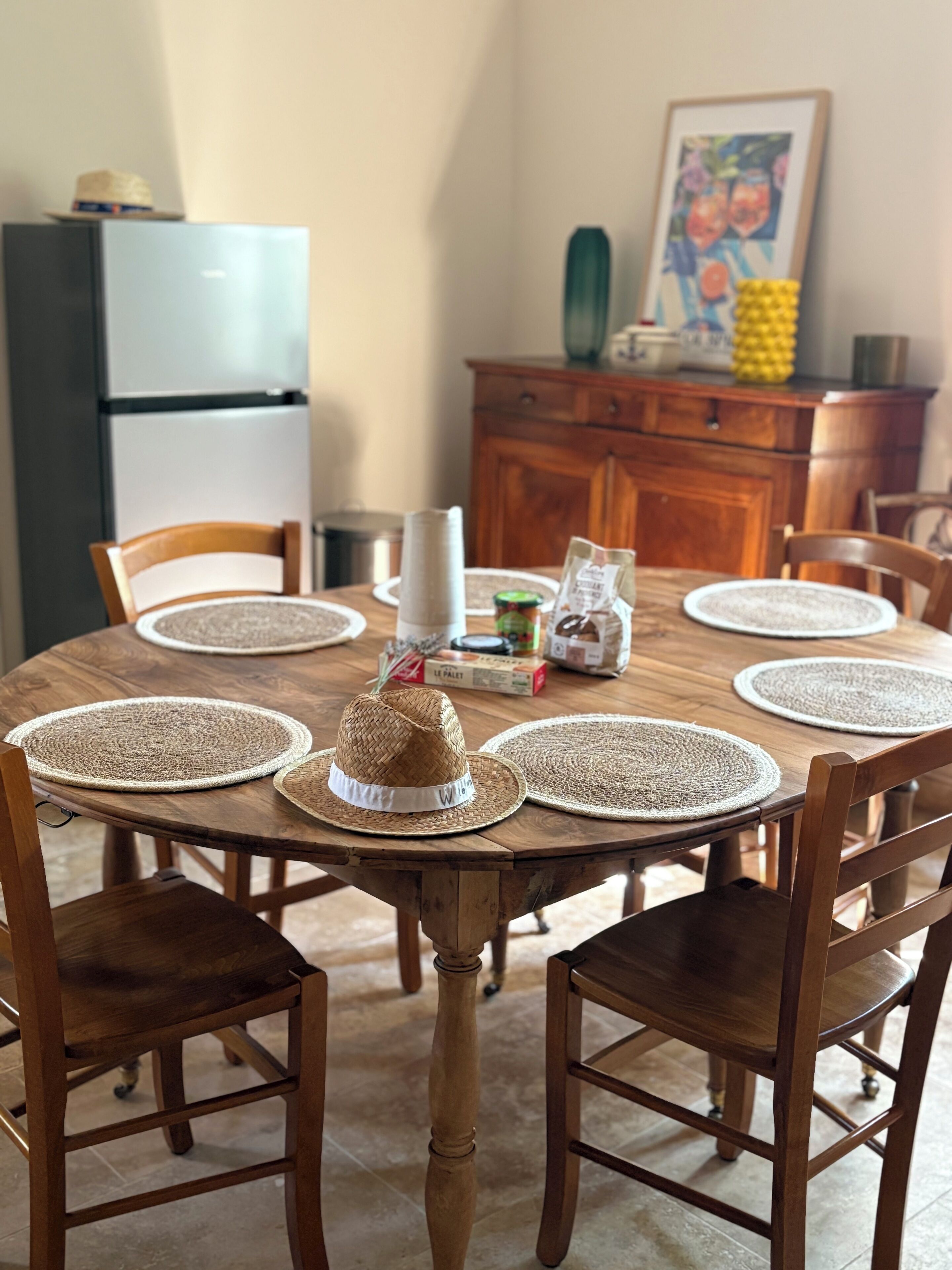 A wooden dining table with woven placemats, a woven hat, and a decorative item on the table.