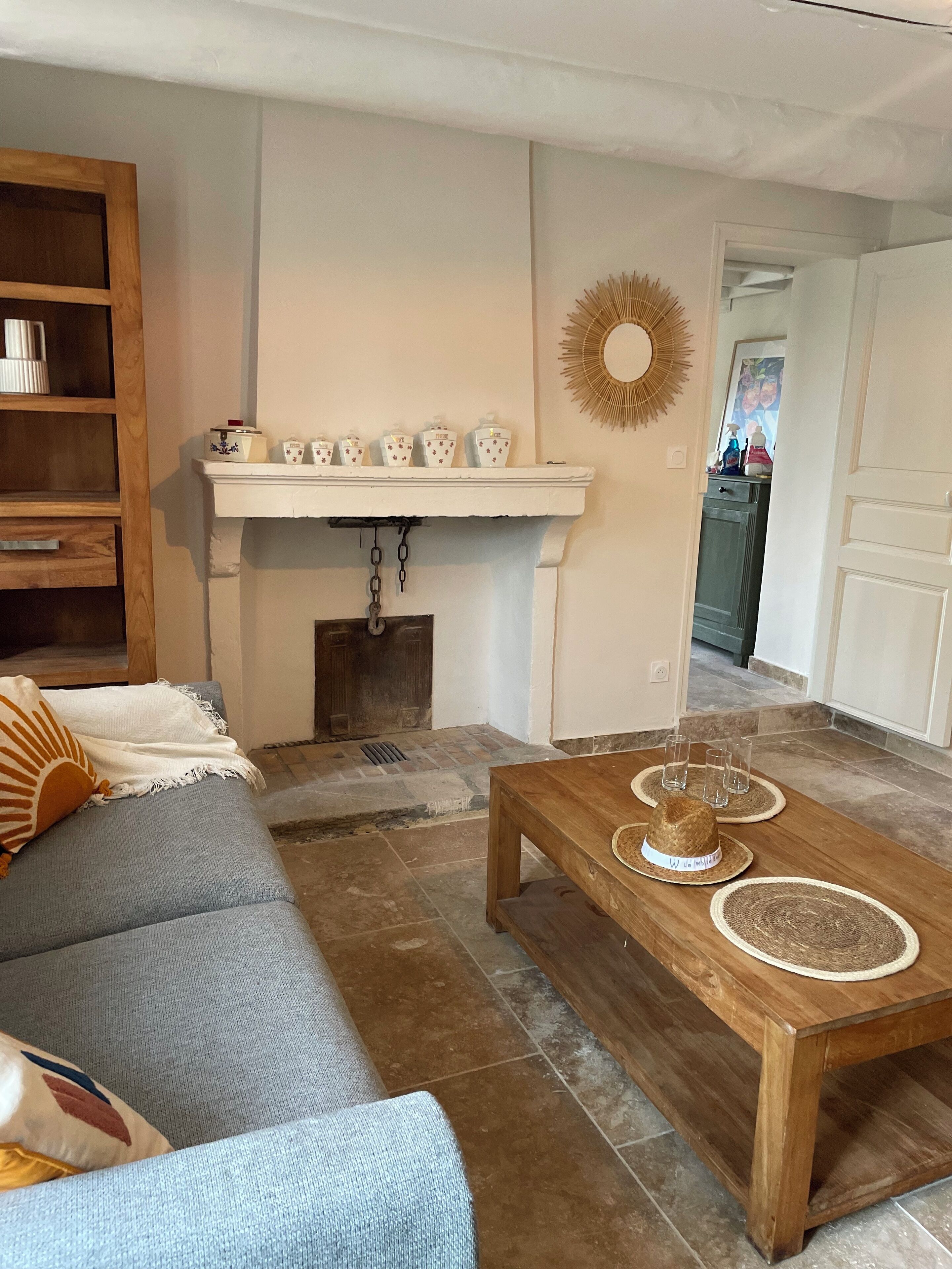 A living room with a sofa, coffee table, fireplace, and a shelf with decorative items.