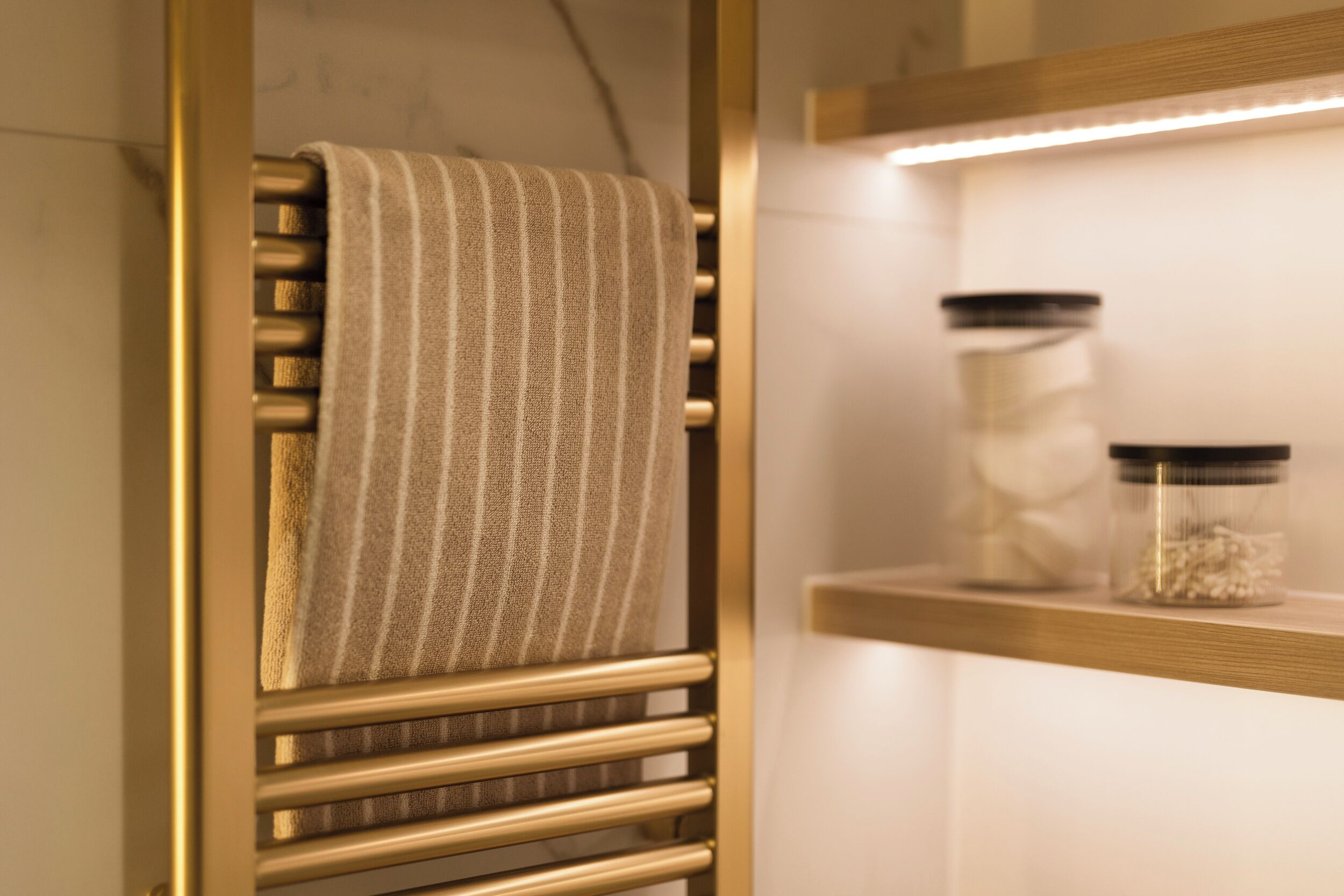 A bathroom with a towel rack, a shelf with jars, and a wooden shelf.