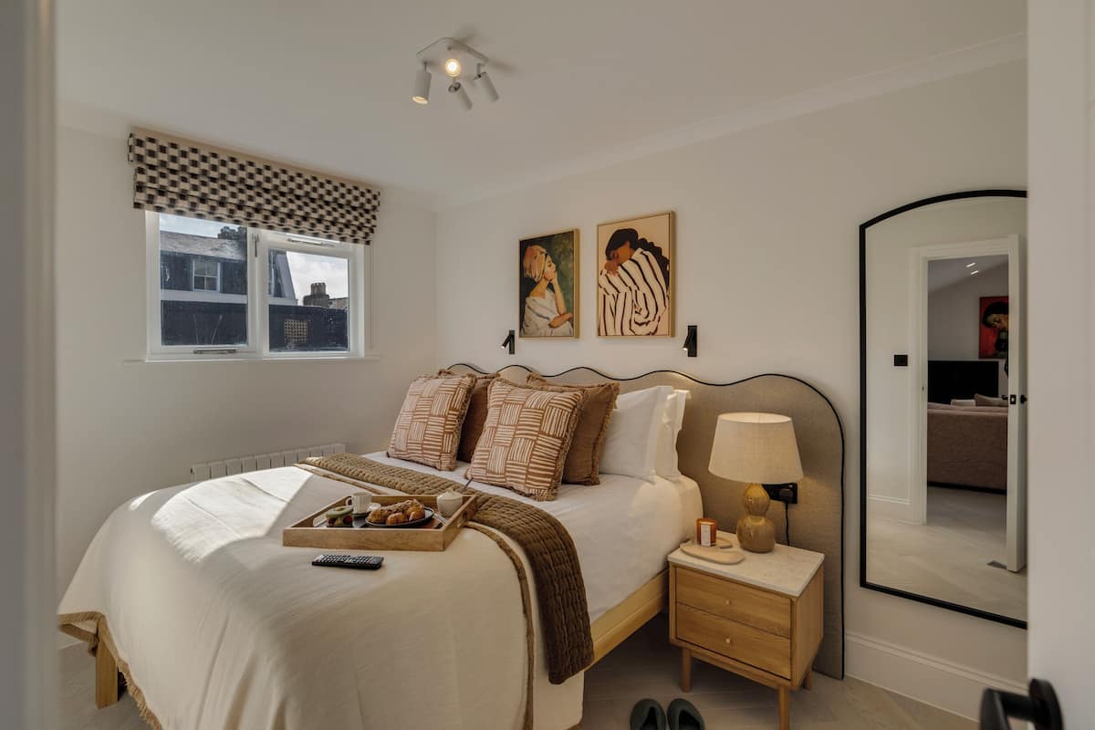 Quarto com cama grande, mesa de cabeceira, abajur e espelho.