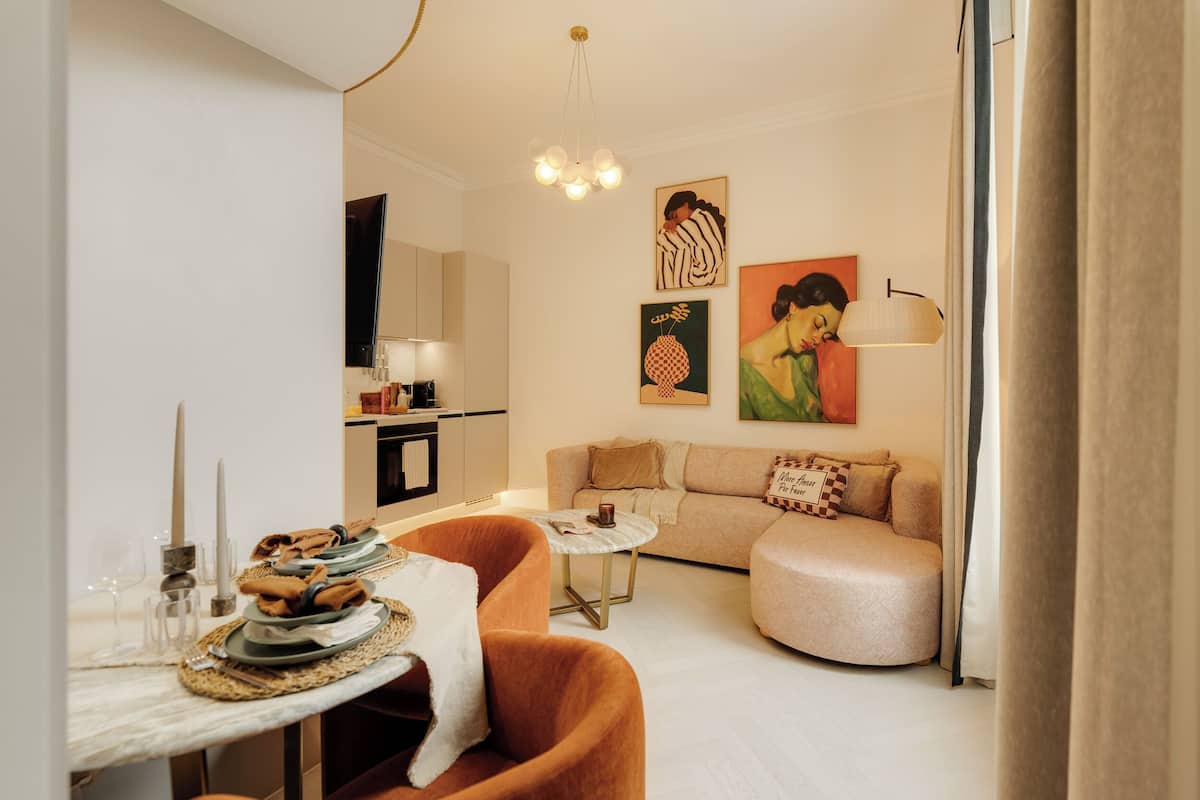 Uma sala de estar moderna com uma mesa de centro redonda, um sofá e um espaço de jantar com uma mesa posta para dois.