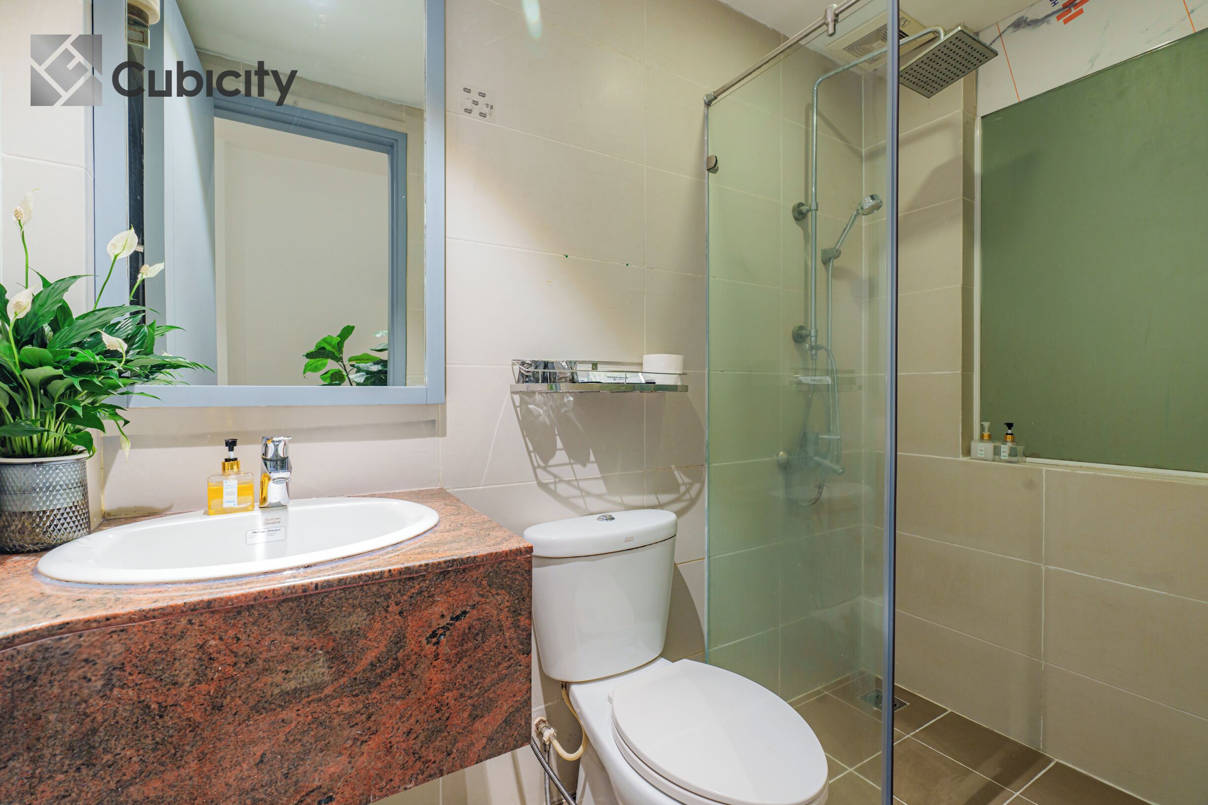 Ein modernes Badezimmer mit einer Granit-Arbeitsplatte, einem weißen Waschbecken, einer Toilette und einer Duschkabine.