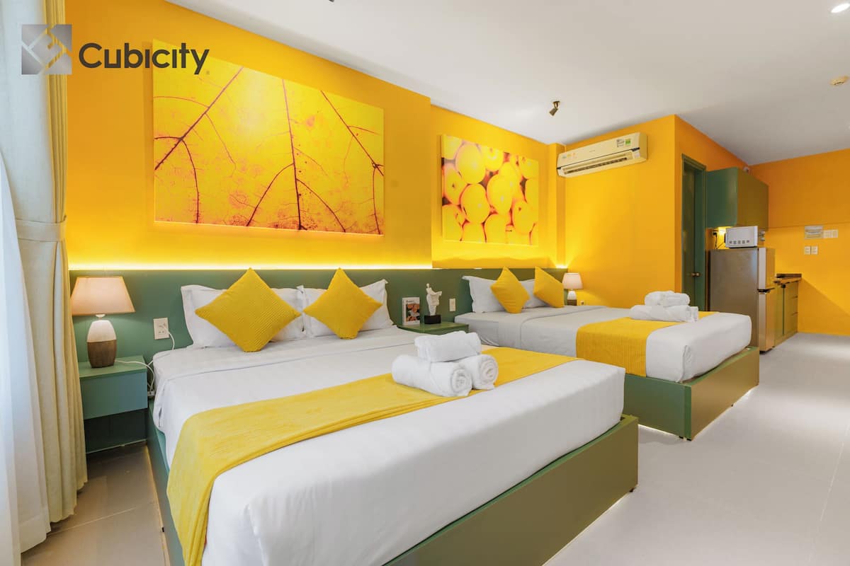 A hotel room with two beds, yellow bedding, and artwork on the walls.