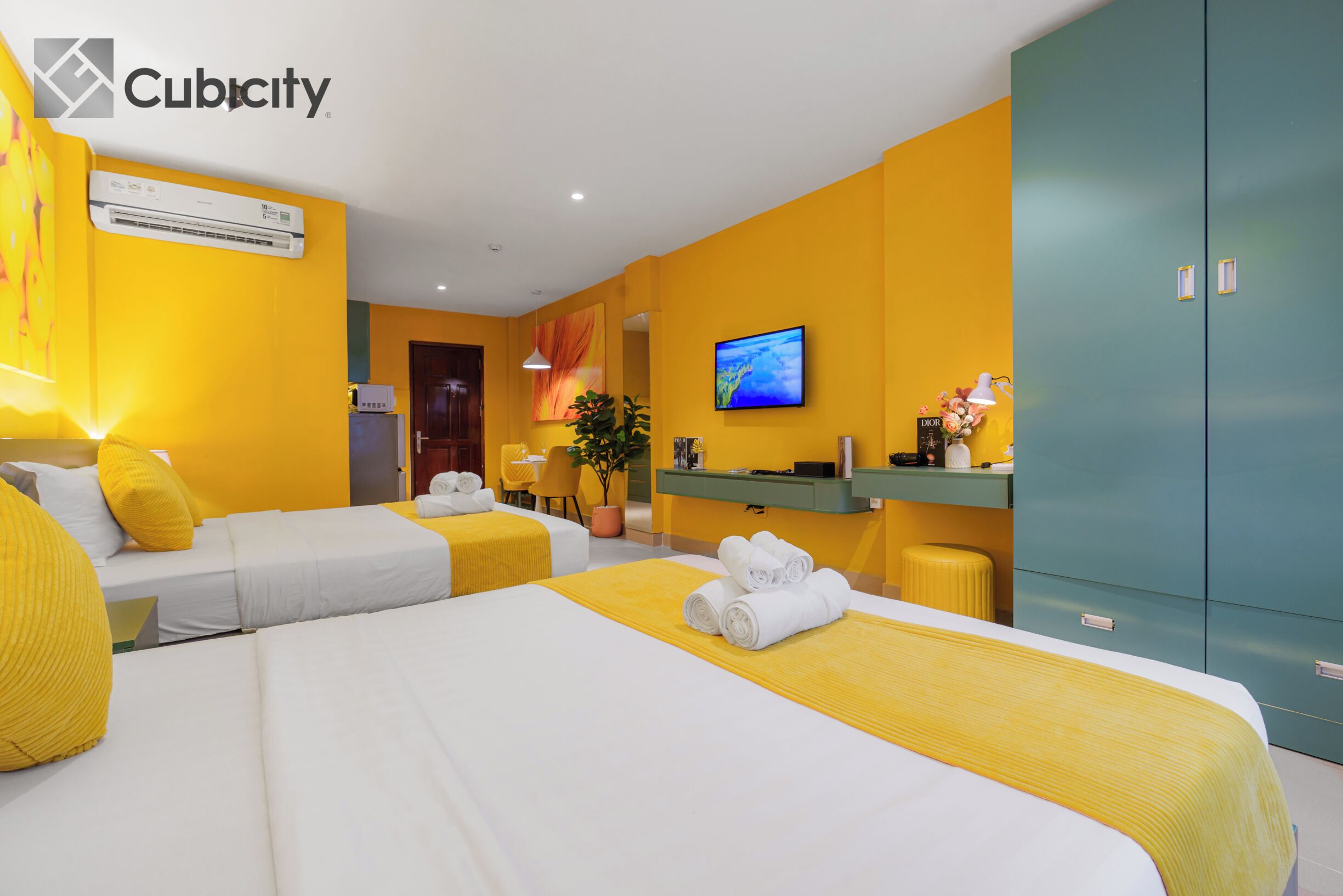 A hotel room with two beds, a desk, a television, and a wardrobe.