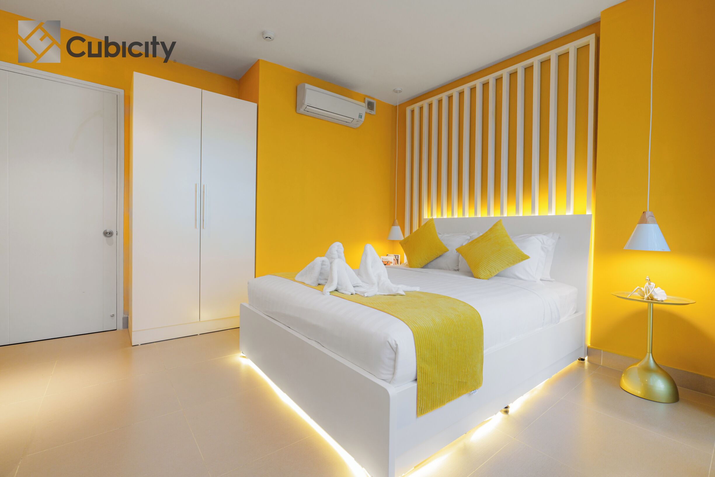 Una habitación de hotel moderna con cama, mesitas de noche, armario y aire acondicionado instalado en la pared.