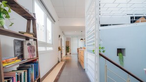 A modern interior with a long hallway, wooden bookshelves, and a staircase.