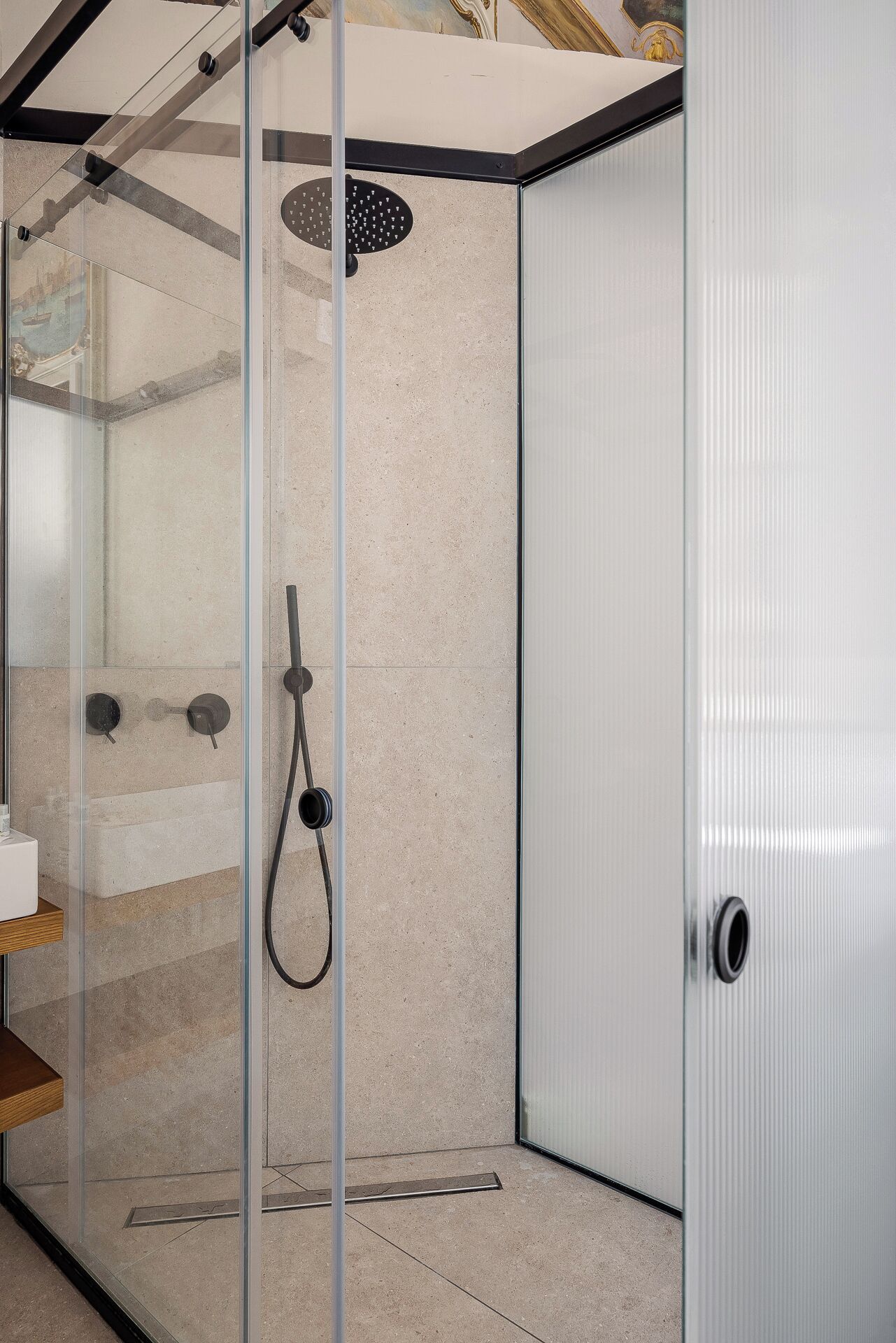 Et moderne bruseområde med glasdør, brusehoved og betjeningspanel.