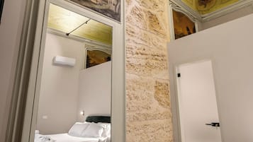 Una habitación con cama, espejo, puerta y pared con textura.