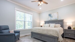 A bedroom with a bed, nightstands, a chair, a window, and a ceiling fan. - Lofty Lakeside Cottage – 2 BR, 2.5BA, Sleeps 8! (Greenwood)