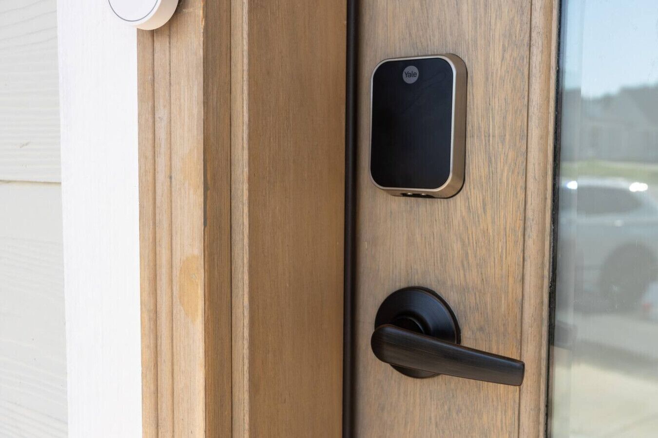 A wooden door with a Yale smart lock and a black handle.