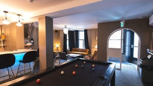 A pool table with balls, a bar area, a sofa, and a window. - Student Residence in the Heart of Montreal (Montréal)