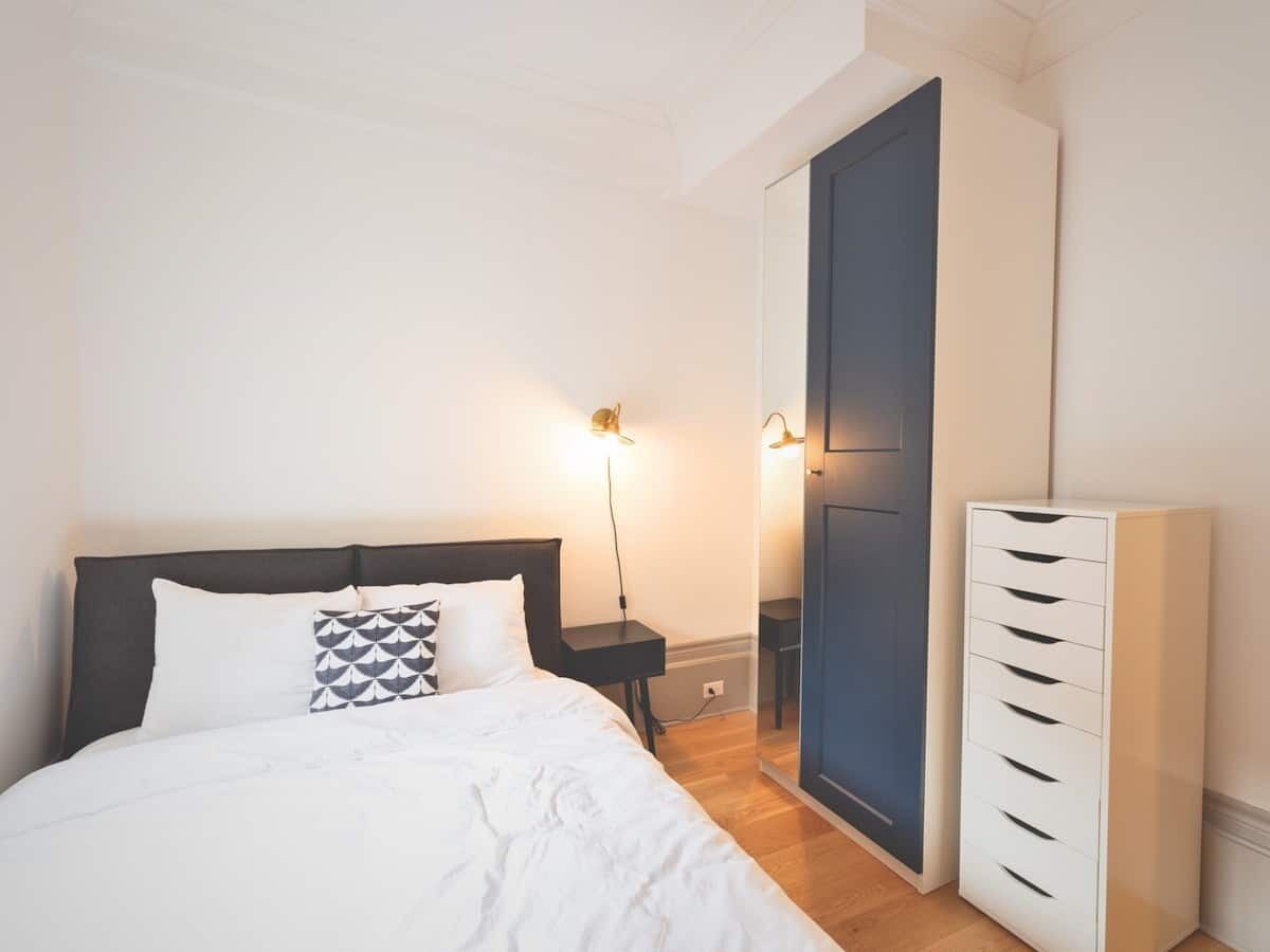 Un dormitorio con cama, mesitas de noche, armario y espejo.