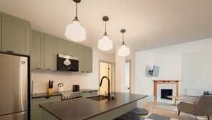 A modern kitchen with a central island, bar stools, a fireplace, and a checkered floor. - Student Residence in the Heart of Montreal (Montréal)