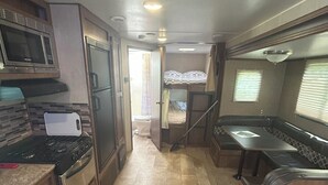 A compact RV kitchen with a microwave, stove, and refrigerator.