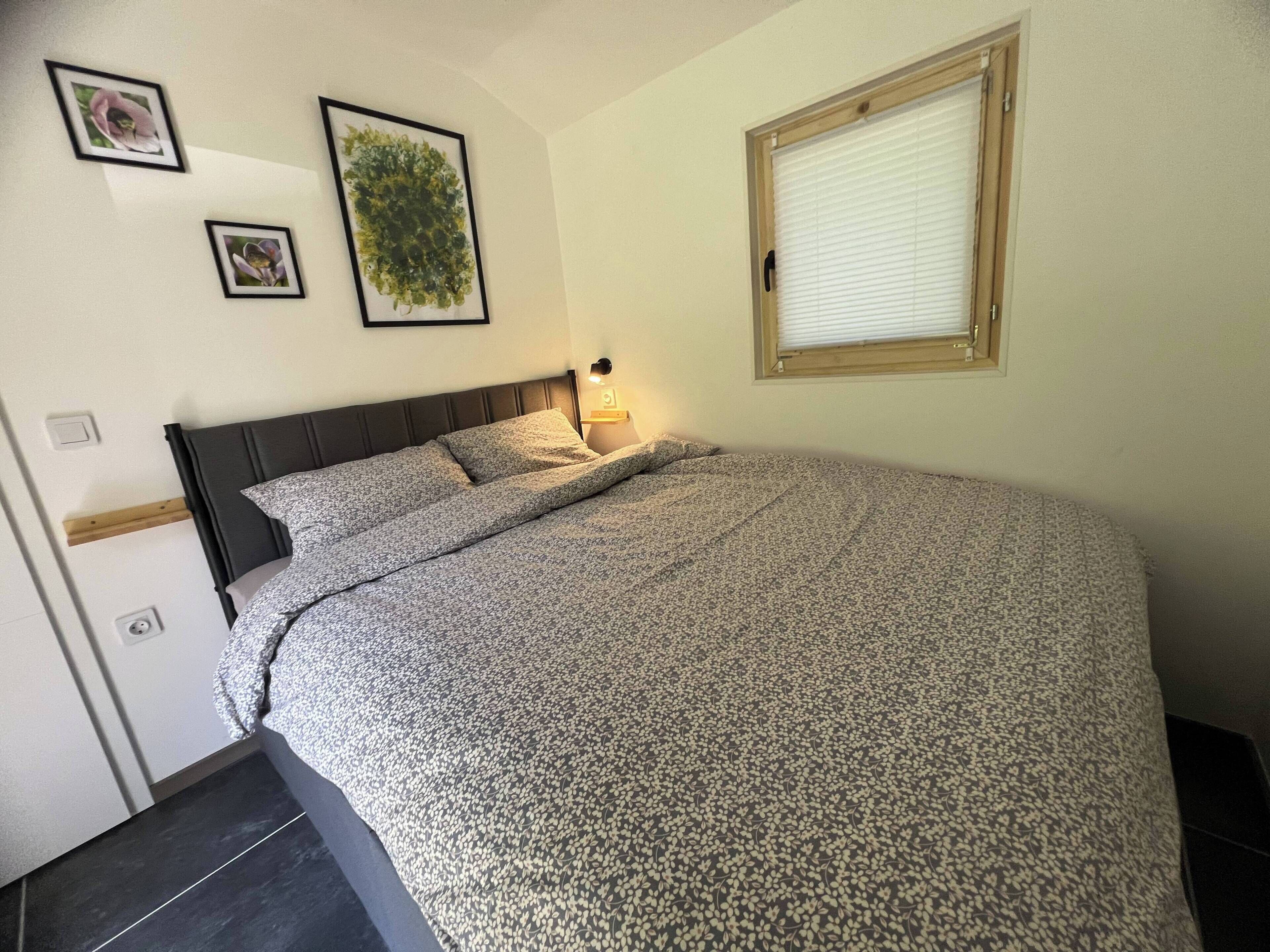 Ein Schlafzimmer mit einem Bett, einem Nachttisch, einer Wandlampe und gerahmten Bildern.
