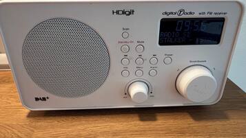 A radio with a digital display, multiple buttons, and a speaker.