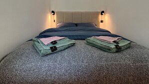 Une chambre à coucher avec un lit, deux lampes fixées au mur et une fenêtre.