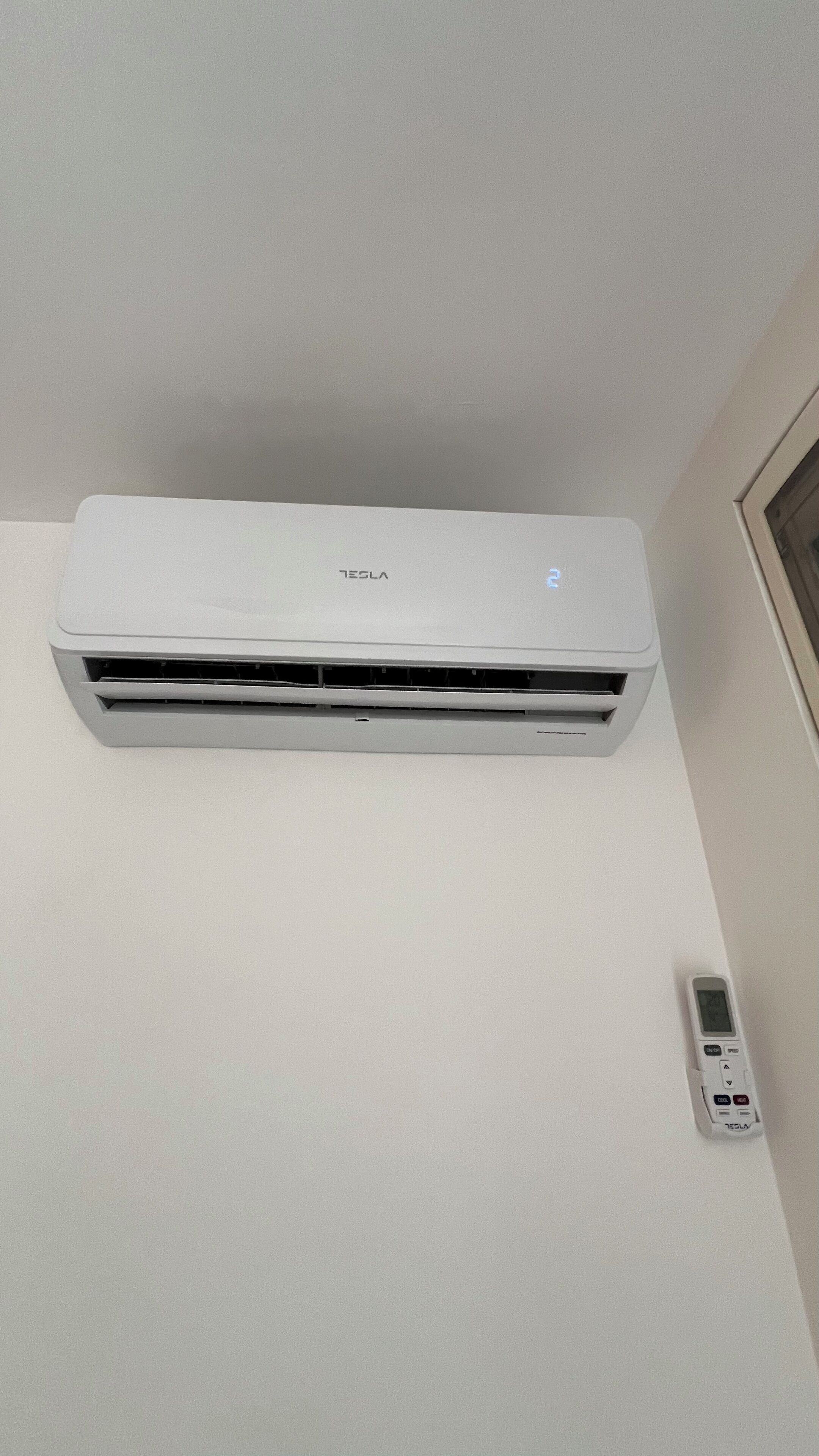 Un aire acondicionado blanco instalado en la pared, con su control remoto a un lado.