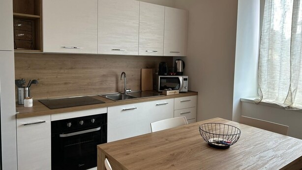Una cocina moderna con armarios blancos, encimera de madera, un lavabo, una estufa y un microondas.