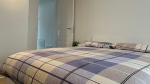 Un dormitorio con cama, puerta y lámpara.