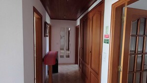 A hallway with wooden doors, a red bench, and a wall-mounted mirror.