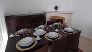 A dining room with a dark wooden table set for six, white plates, and purple glassware.
